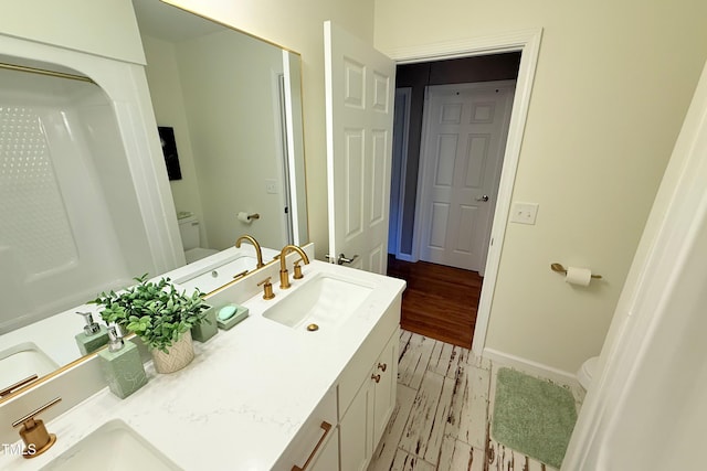 3141 Wagoner Ln Unit 09, Graham, NC 27253 - bathroom featuring toilet, double vanity, wood finished floors, and baseboards