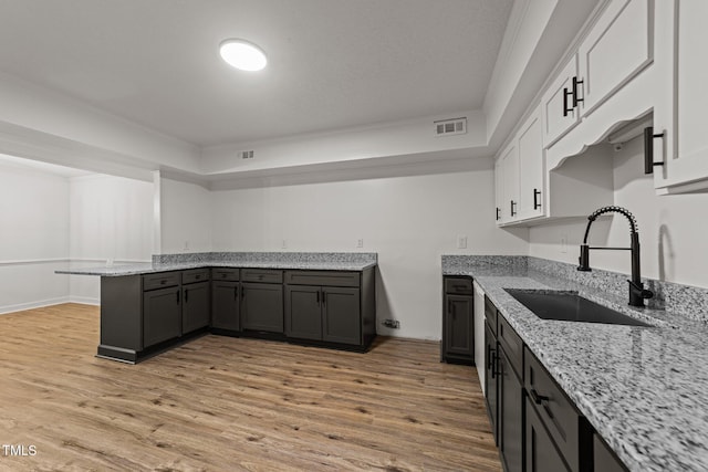 3204 Manor Ridge Dr, Raleigh, NC 27603 - kitchen featuring a sink, light stone counters, a peninsula, light wood finished floors, and ornamental molding