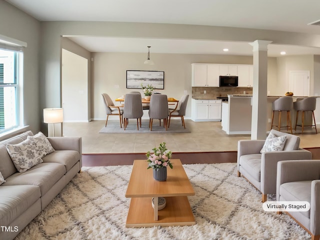 living area featuring recessed lighting, decorative columns, and baseboards