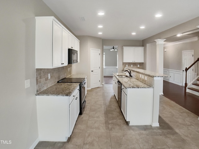 kitchen featuring stainless steel range with electric stovetop, black microwave, a sink, tasteful backsplash, and light stone countertops