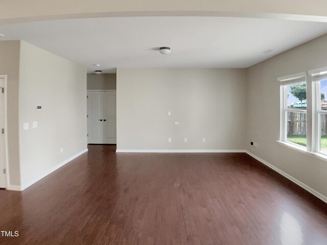 empty room featuring dark wood-style floors and baseboards
