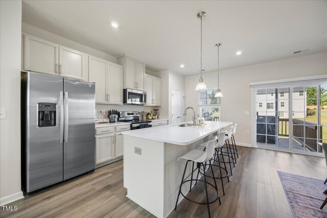 926 Romeria Dr, Durham, NC 27713 - kitchen with stainless steel appliances, a sink, a kitchen island with sink, light countertops, and wood finished floors