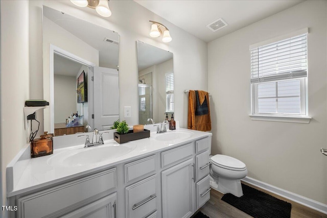 926 Romeria Dr, Durham, NC 27713 - bathroom with toilet, double vanity, wood finished floors, a shower with door, and baseboards