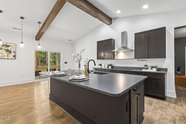 13417 New Light Rd, Raleigh, NC 27614 - kitchen with wall chimney range hood, dark countertops, light wood-type flooring, a kitchen island with sink, and decorative light fixtures