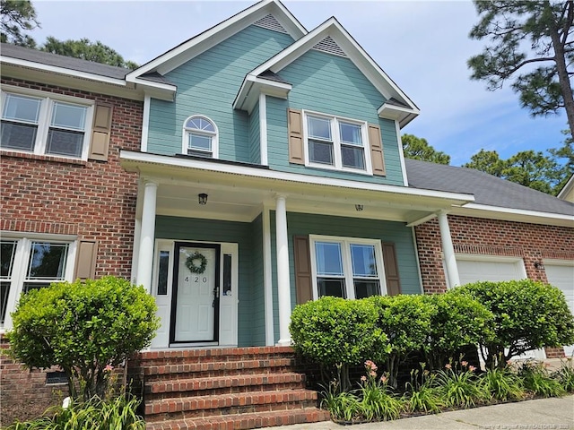 view of front of home featuring a garage, brick siding, and covered porch