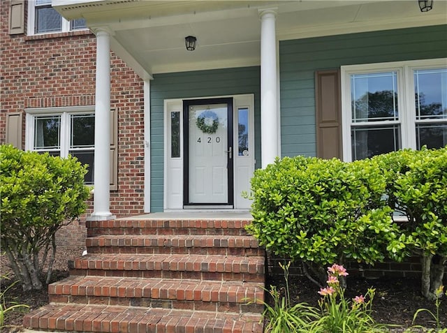 property entrance featuring brick siding and a porch