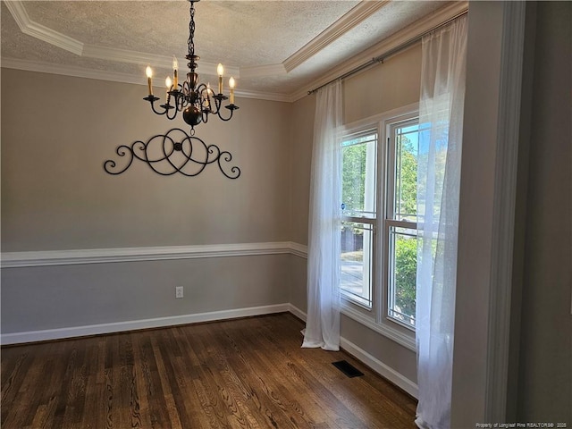 unfurnished room with a chandelier, healthy amount of natural light, dark wood finished floors, a textured ceiling, and crown molding