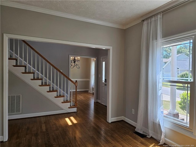 entrance foyer with wood finished floors, stairway, a chandelier, a textured ceiling, and baseboards