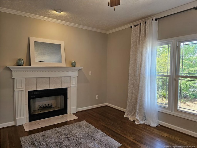 living area with dark wood-type flooring, a tile fireplace, baseboards, crown molding, and a textured ceiling