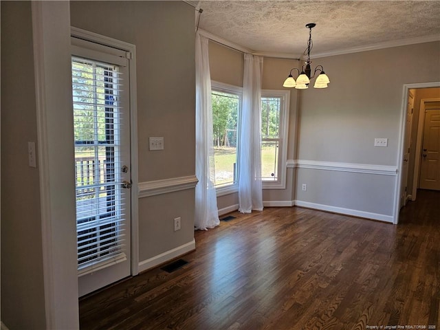unfurnished dining area featuring a chandelier, a textured ceiling, dark wood-style floors, crown molding, and baseboards