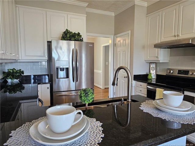 kitchen featuring appliances with stainless steel finishes, under cabinet range hood, backsplash, white cabinets, and dark stone countertops