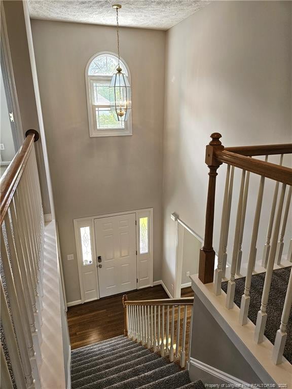 foyer entrance with a chandelier, wood finished floors, stairs, and a textured ceiling