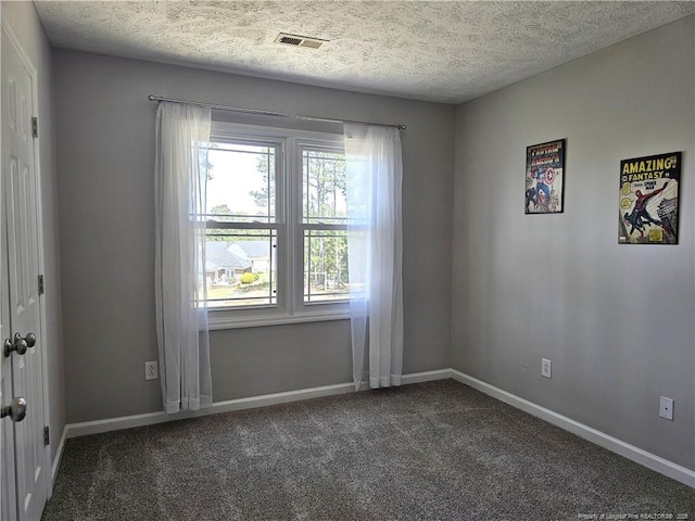 spare room featuring dark carpet, healthy amount of natural light, baseboards, and a textured ceiling