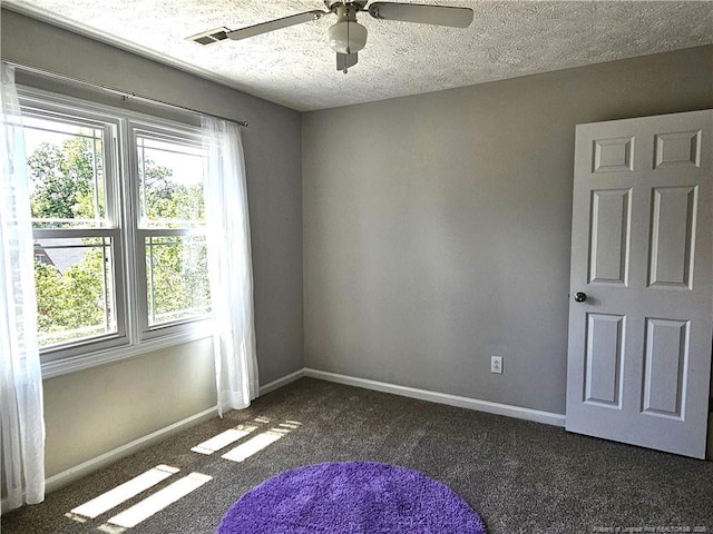 carpeted spare room with a ceiling fan, plenty of natural light, baseboards, and a textured ceiling