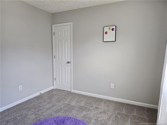 spare room with carpet floors, baseboards, and a textured ceiling