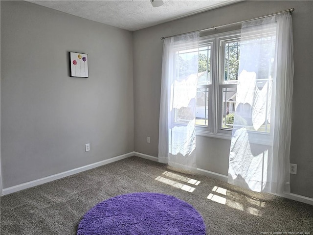 unfurnished room with carpet, a textured ceiling, and baseboards