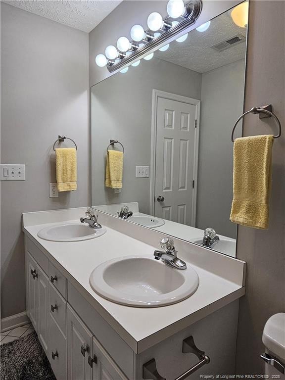 bathroom featuring a textured ceiling, double vanity, and tile patterned floors