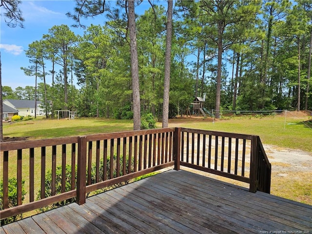 deck featuring a playground, a yard, and view of scattered trees