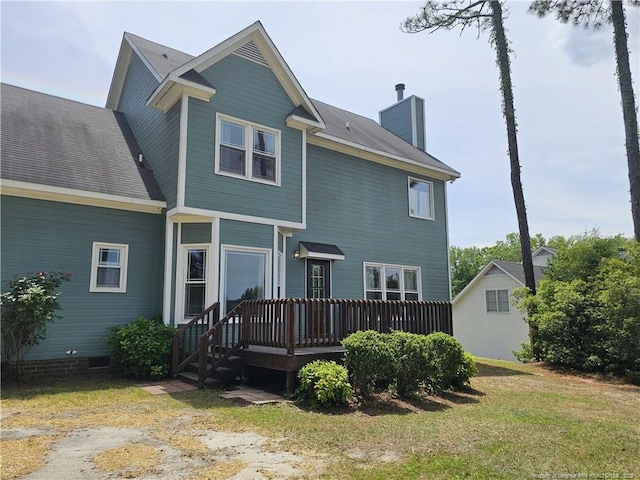 rear view of house featuring a chimney, a wooden deck, and a yard