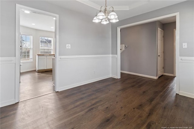 unfurnished dining area with a chandelier, dark wood-style flooring, and ornamental molding