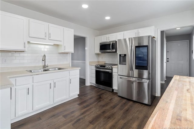 kitchen featuring stainless steel appliances, a sink, light countertops, white cabinets, and tasteful backsplash