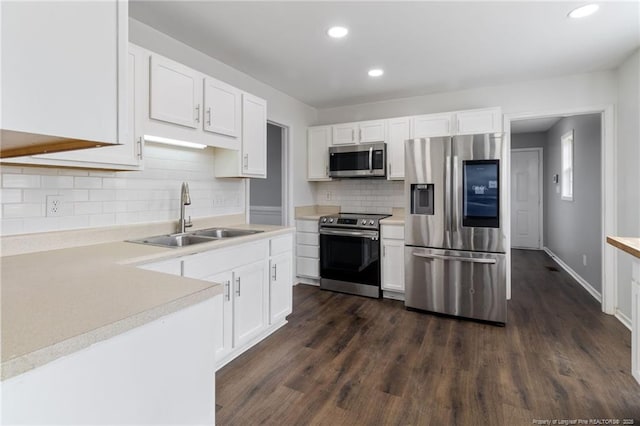 kitchen featuring appliances with stainless steel finishes, a sink, white cabinetry, recessed lighting, and backsplash