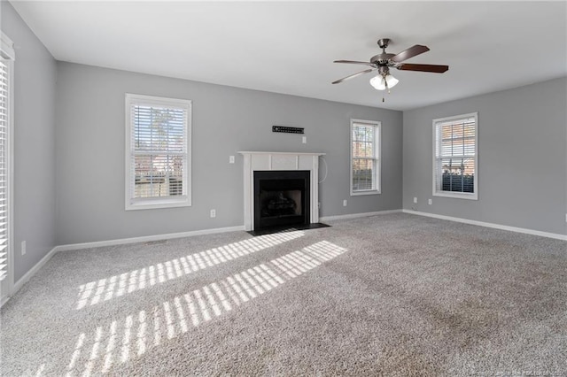 unfurnished living room featuring carpet floors, healthy amount of natural light, a fireplace with flush hearth, and ceiling fan