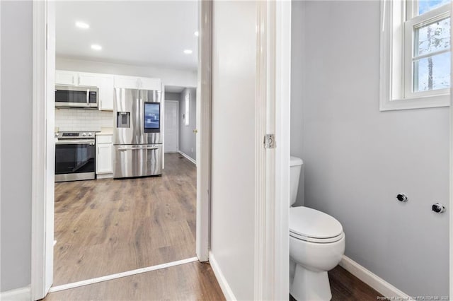 bathroom with baseboards, wood finished floors, backsplash, and recessed lighting