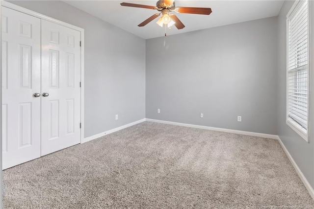 unfurnished bedroom with carpet, baseboards, ceiling fan, and a closet