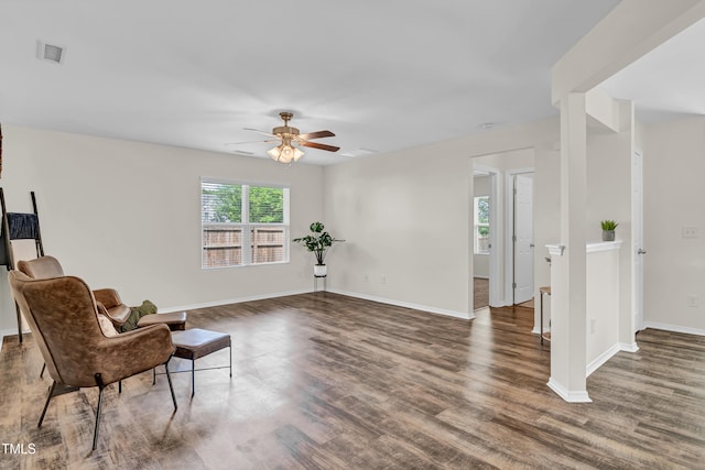 living area with a ceiling fan, wood finished floors, and baseboards