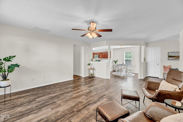 living area with wood finished floors, a ceiling fan, and baseboards