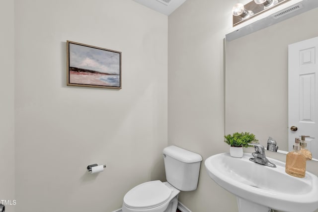 bathroom featuring a sink, toilet, and baseboards