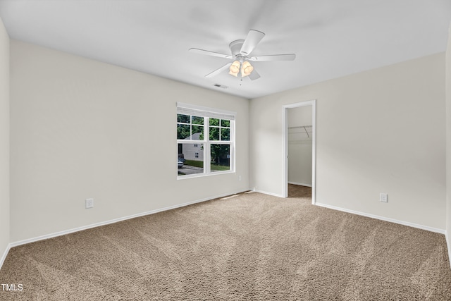 unfurnished bedroom with carpet flooring, baseboards, and a walk in closet