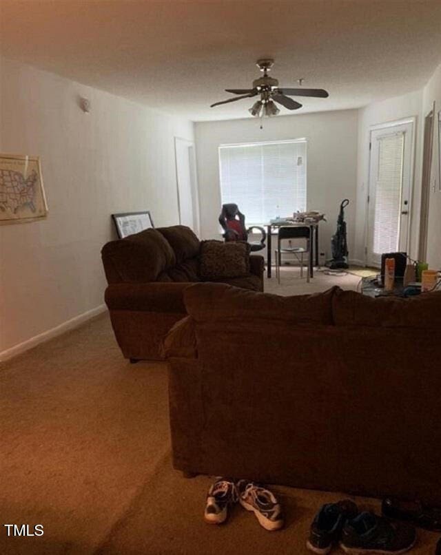living area with carpet floors, a ceiling fan, and baseboards