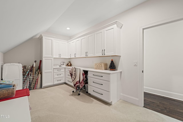 office space featuring built in desk, baseboards, recessed lighting, lofted ceiling, and light carpet