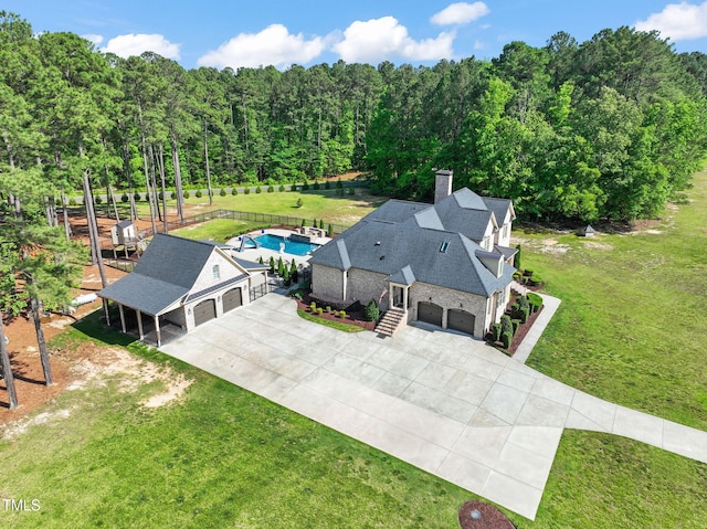 aerial view of property and surrounding area with a pool and a heavily wooded area
