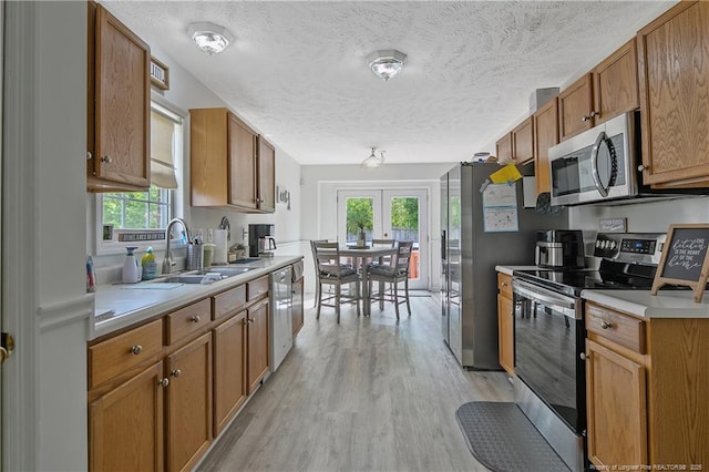 4829 Miranda Dr, Hope Mills, NC 28348 - kitchen with stainless steel appliances, a sink, light wood-style floors, healthy amount of natural light, and a textured ceiling