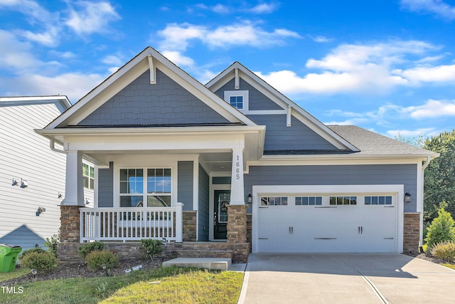 craftsman-style home with stone siding, covered porch, concrete driveway, and an attached garage