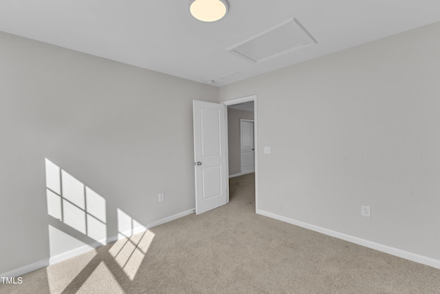 spare room featuring carpet floors, baseboards, and attic access