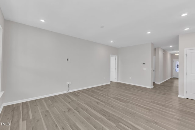 empty room featuring light wood finished floors, baseboards, and recessed lighting