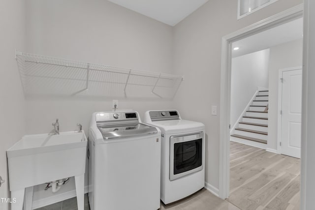 washroom with washing machine and dryer, light wood-type flooring, and baseboards