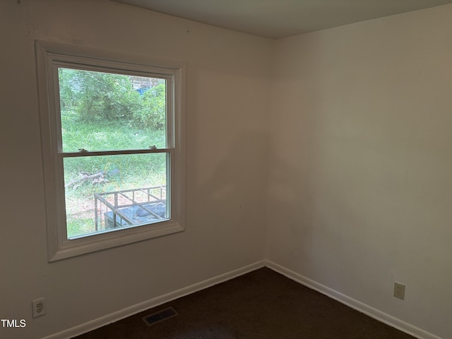 unfurnished room with baseboards and dark colored carpet