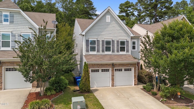 2057 Tanners Mill Dr, Durham, NC 27703 - view of front of house featuring a garage, driveway, stone siding, and a shingled roof