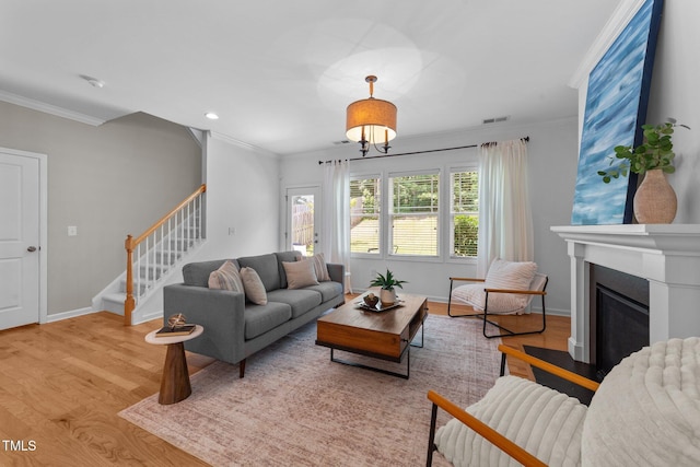 2057 Tanners Mill Dr, Durham, NC 27703 - living area featuring ornamental molding, stairway, wood finished floors, baseboards, and a glass covered fireplace
