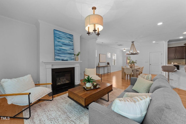 2057 Tanners Mill Dr, Durham, NC 27703 - living area featuring a chandelier, ornamental molding, light wood-style flooring, a fireplace with flush hearth, and baseboards