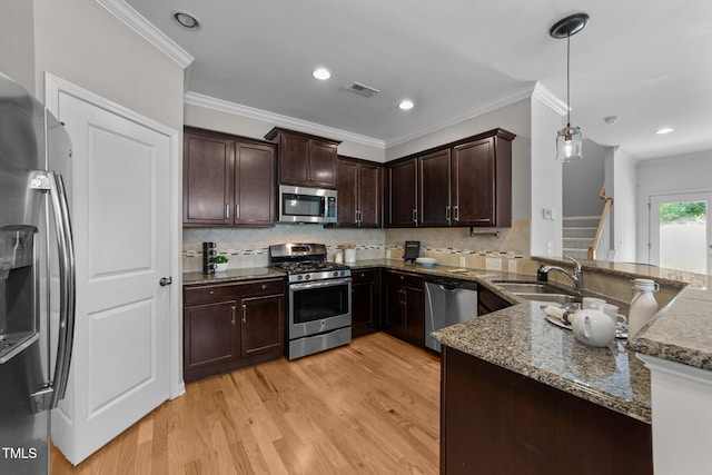 2057 Tanners Mill Dr, Durham, NC 27703 - kitchen with appliances with stainless steel finishes, a sink, light wood-style flooring, dark stone countertops, and dark brown cabinets