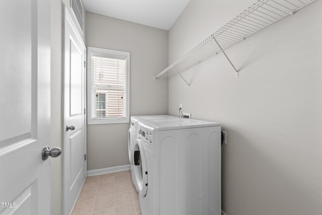 2057 Tanners Mill Dr, Durham, NC 27703 - washroom featuring washing machine and clothes dryer, light tile patterned floors, and baseboards