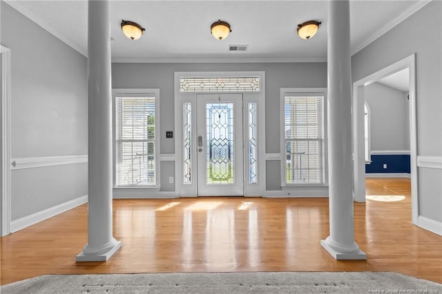 foyer entrance featuring decorative columns, crown molding, wood finished floors, and baseboards