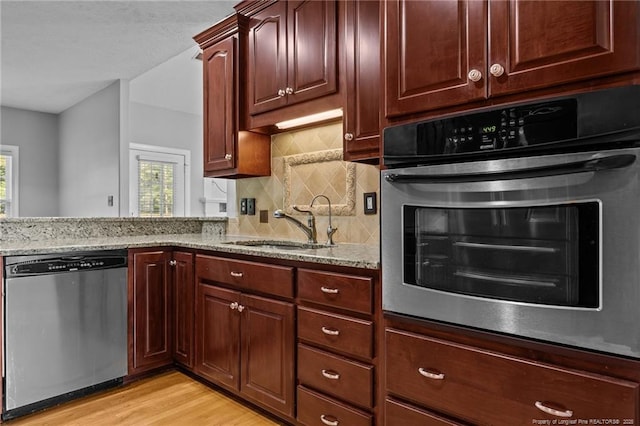kitchen featuring appliances with stainless steel finishes, plenty of natural light, a sink, and light stone countertops