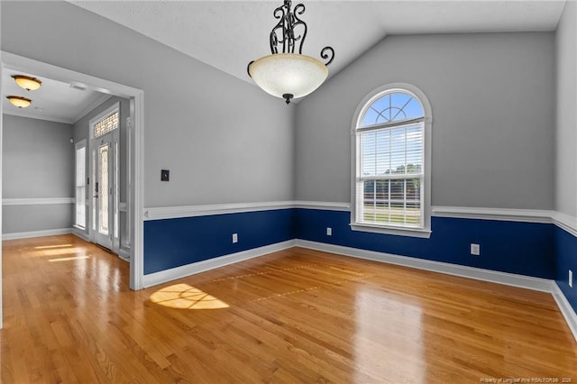 spare room with wood finished floors, vaulted ceiling, and baseboards